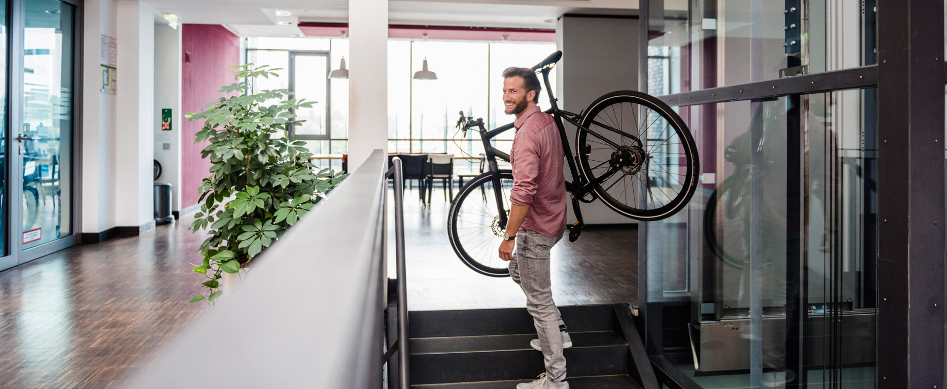 Ein Mann trägt sein Fahrrad die Treppen im Büro hoch.