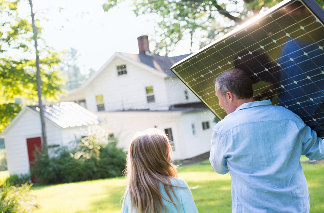 Ein Mann trägt eine Solarzelle und wird von einem Mädchen begleitet.