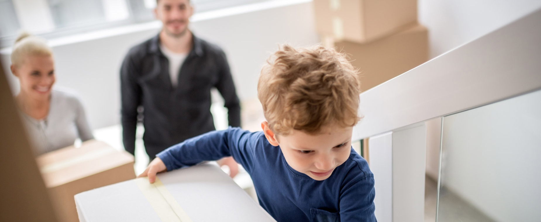 Vater und Sohn tragen Umzugskartons die Treppen hoch.