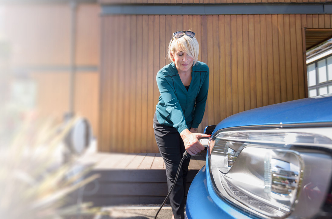 Eine Frau lädt zuhause ihr Elektroauto.