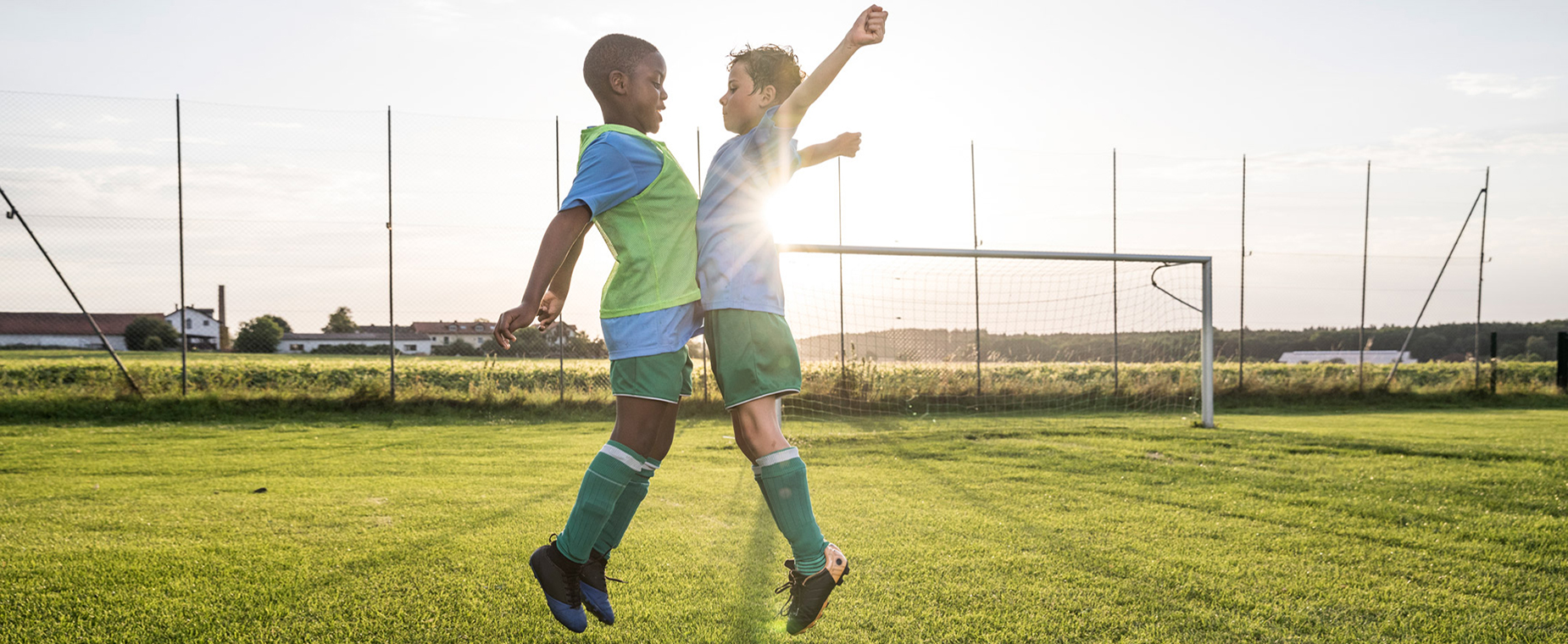 Lachende Kinder beim Spielen auf einem Fußballplatz.